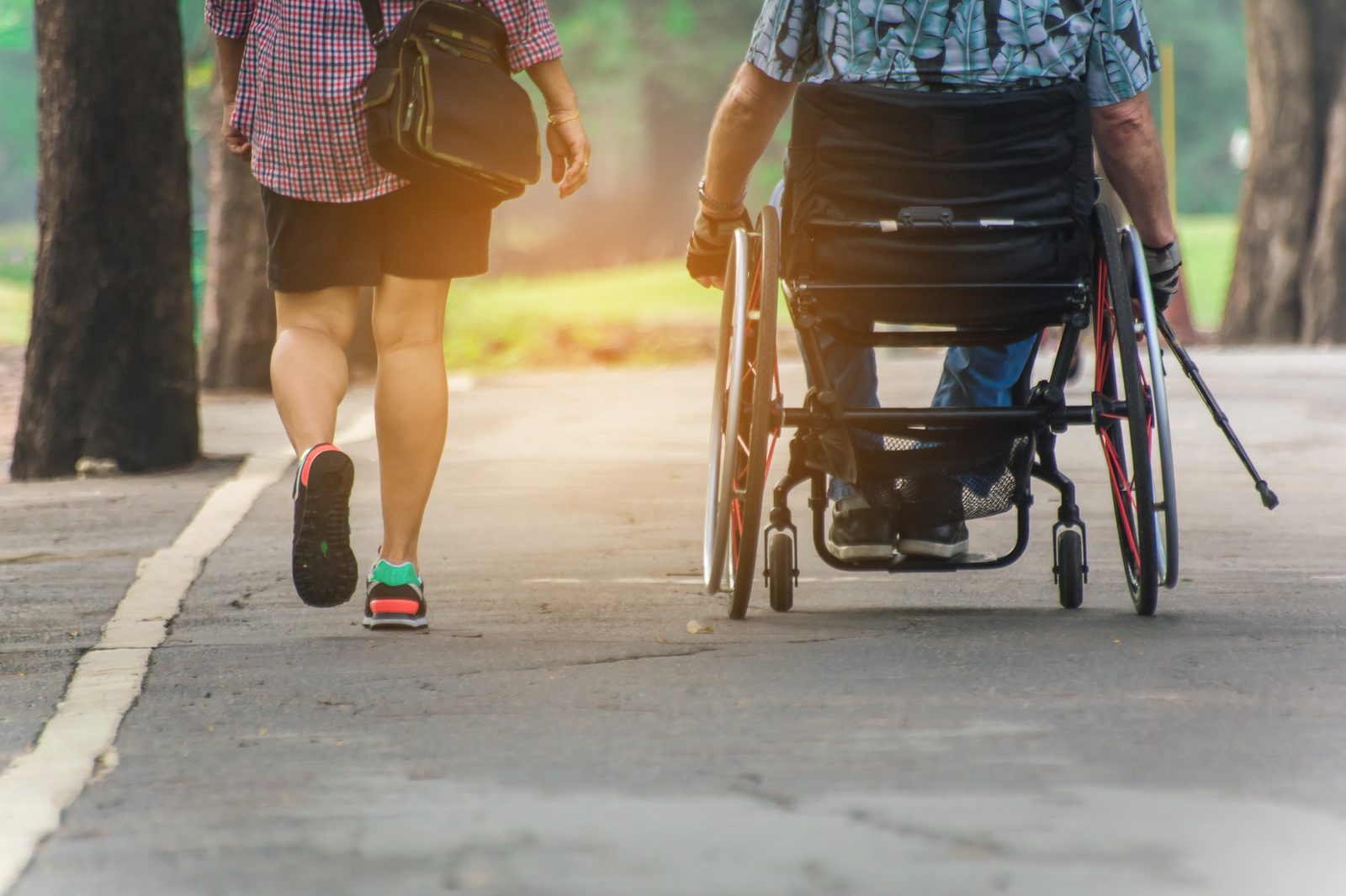 A carer supporting a person doing physical rehabilitation exercises, showing hands-on assistance and encouragement
