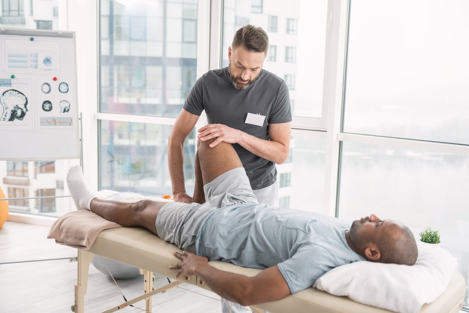 A neuro physiotherapist working on a patient's leg movement on a treatment table